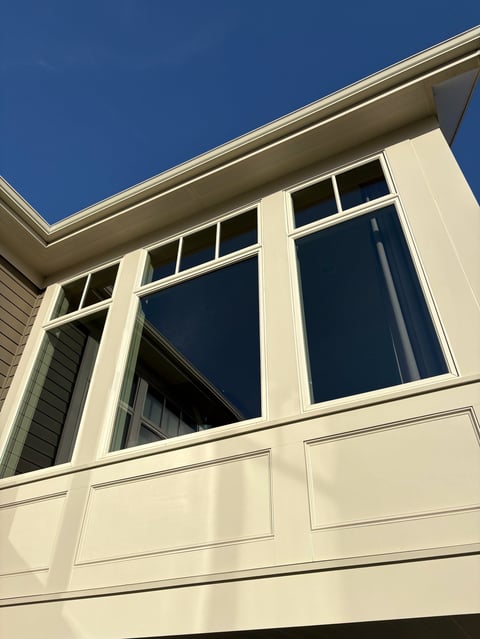 Cream-colored modern house exterior with large windows and dark blue sky above
